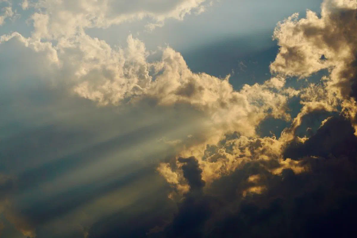 Sunlight piercing through dark clouds, creating a dramatic sky scene with rays of light.