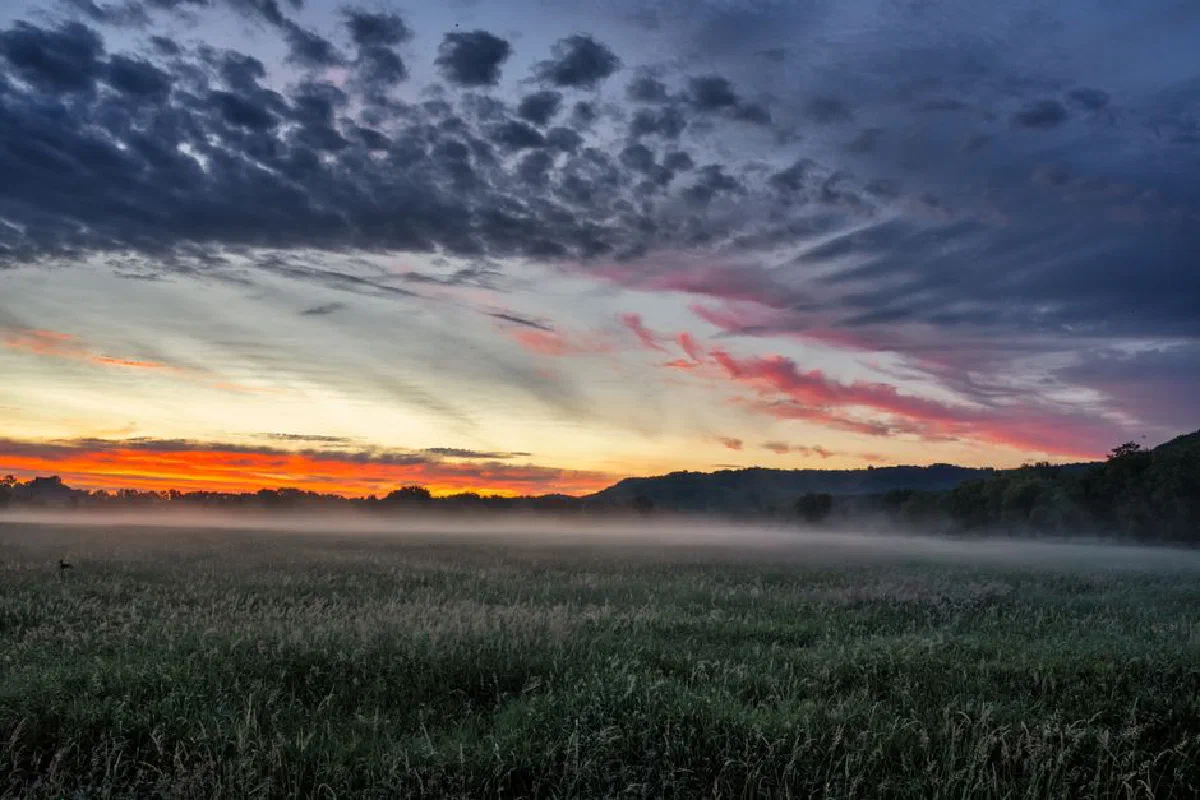 A breathtaking sunset casts vivid colors over a misty field in Modena, Wisconsin, creating a serene rural landscape.