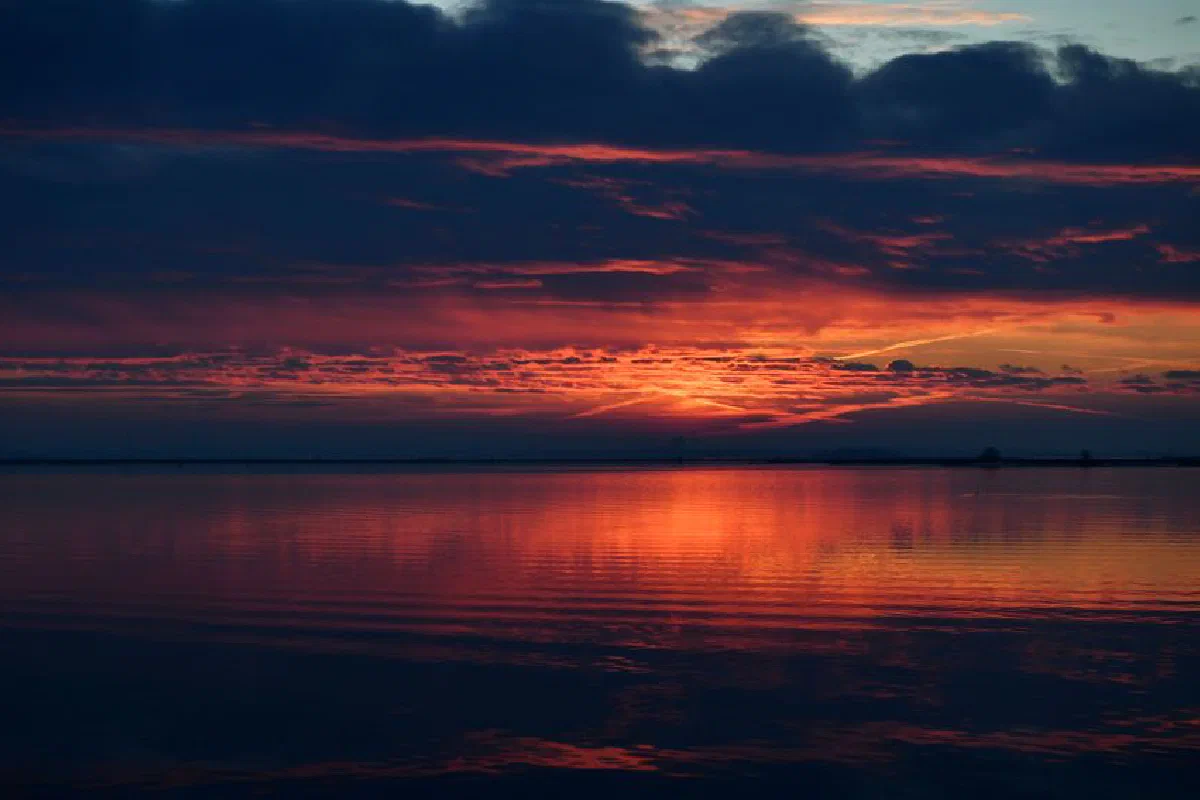 Stunning sunset over a tranquil sea with vivid colors and serene reflections.