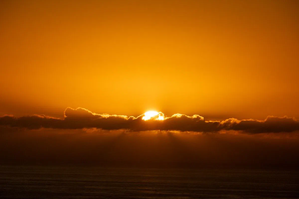 A stunning sunset over the ocean in Cape Town, South Africa, with golden clouds and serene waters.
