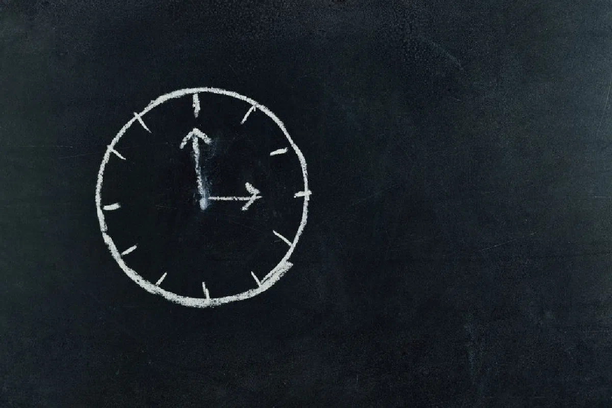 Chalk-drawn clock on a blackboard, symbolizing time and education concepts.