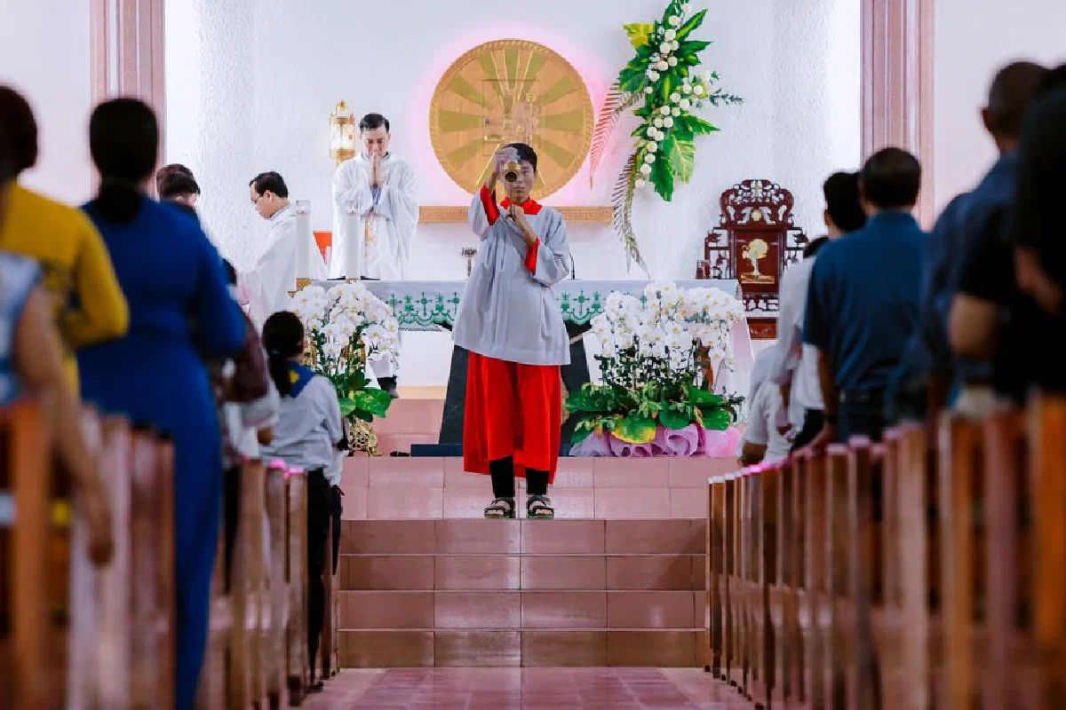 A priest conducts a religious service with a congregation in a church interior.
