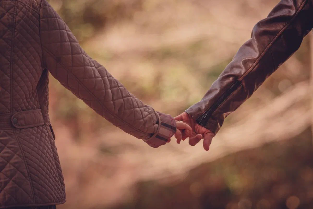 Close-up of a couple holding hands in a romantic outdoor setting.