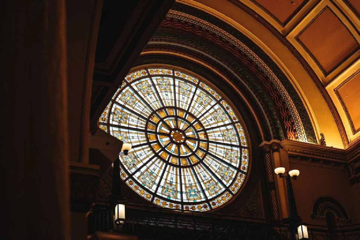 Captivating stained glass window inside a historic church, showcasing intricate design and warm lighting.
