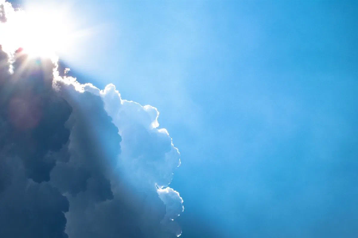 Bright sunlight streams through dramatic clouds in a vivid blue sky.