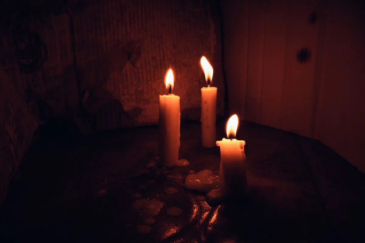Three melting candles create a warm glow in a dark room, epitomizing tranquility.