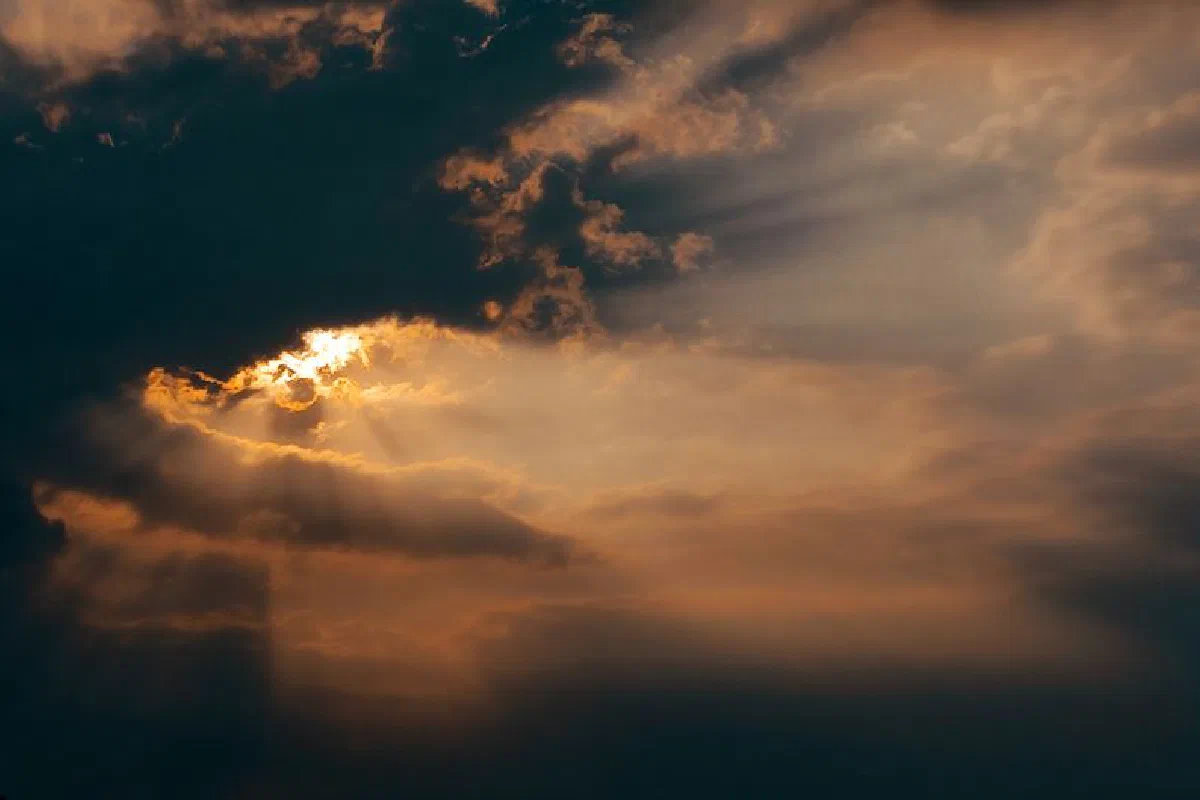 Dramatic clouds with sunlight rays breaking through, creating a beautiful evening sky.