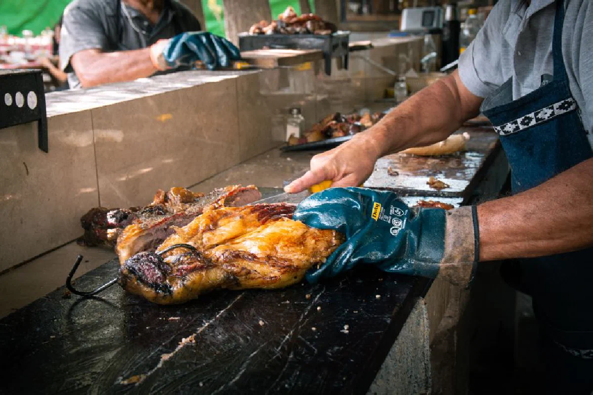 Skillful chef slicing grilled meat at an outdoor barbecue station, showcasing technique and flavor.