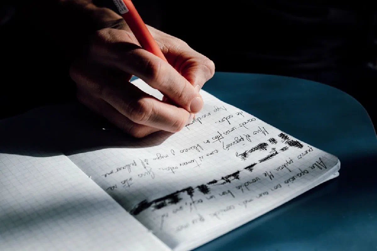 A close-up of a hand writing in a notebook, showing personal notes and reflections.