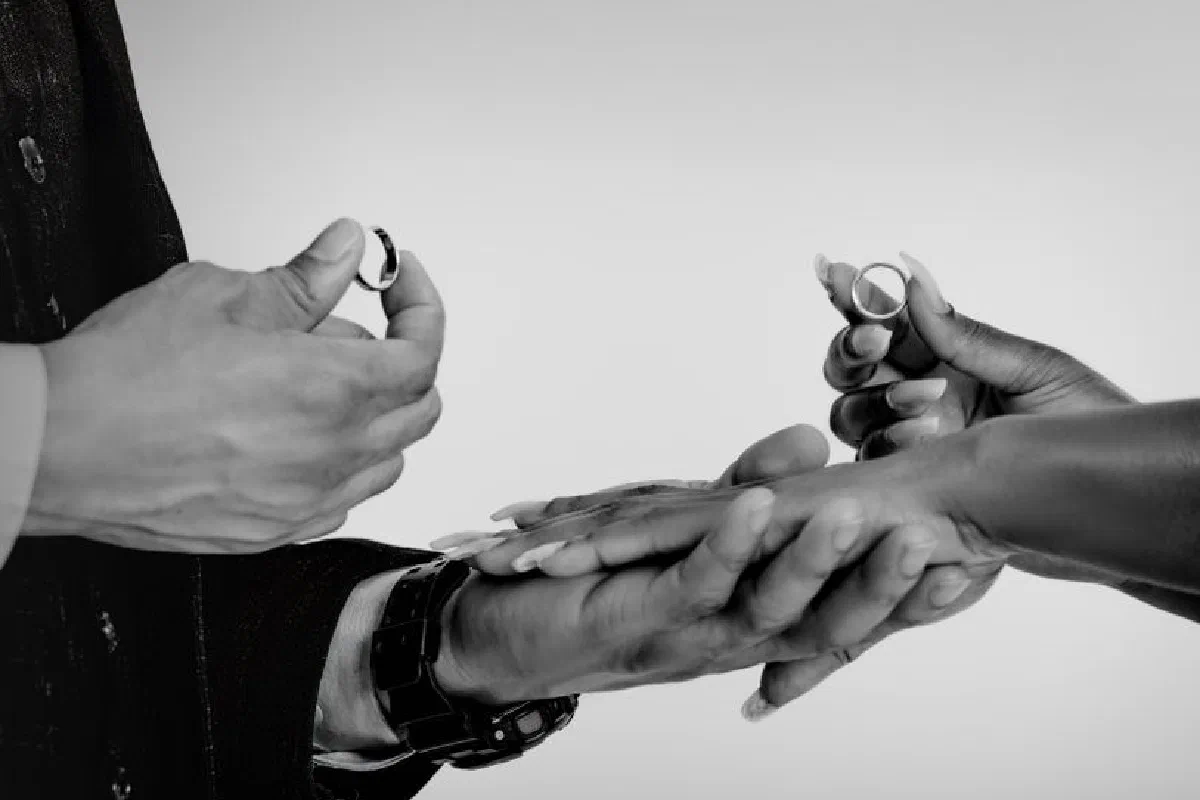 Close-up of hands exchanging wedding rings, symbolizing commitment and love.