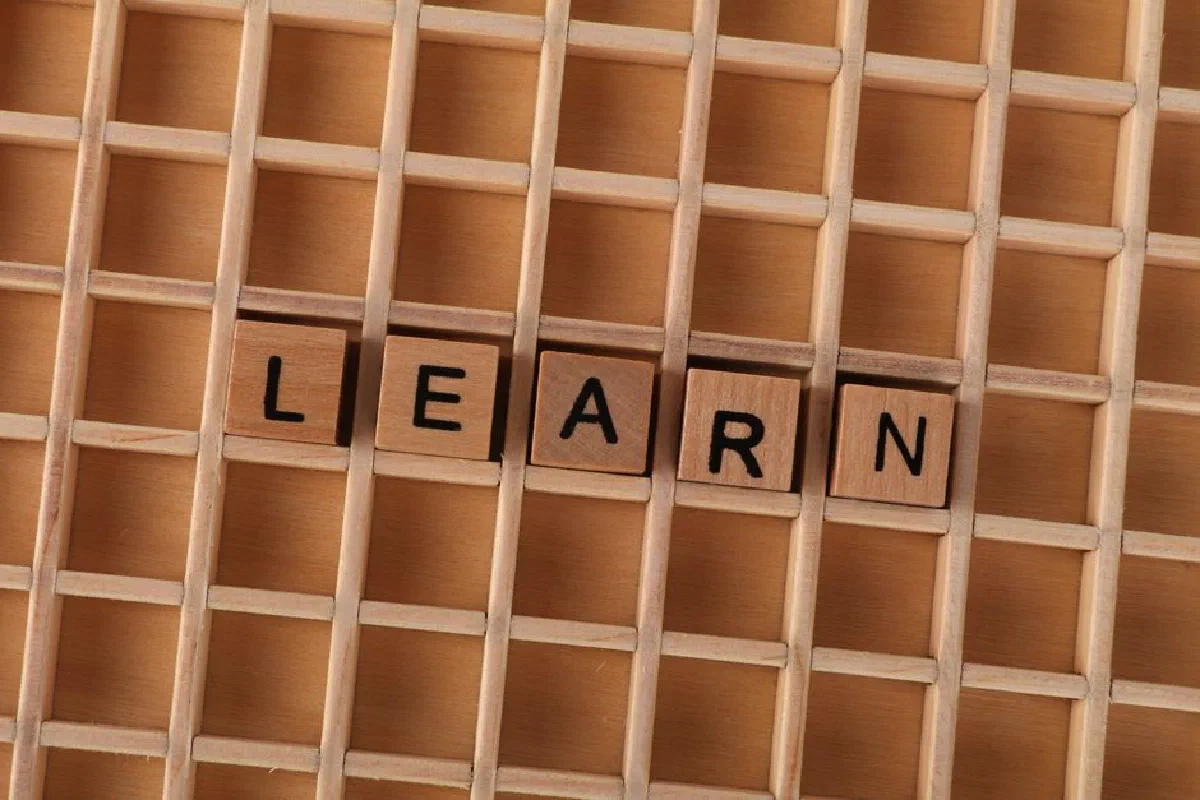 Wooden blocks spelling the word 'LEARN' on a grid-like wooden background. Educational concept.