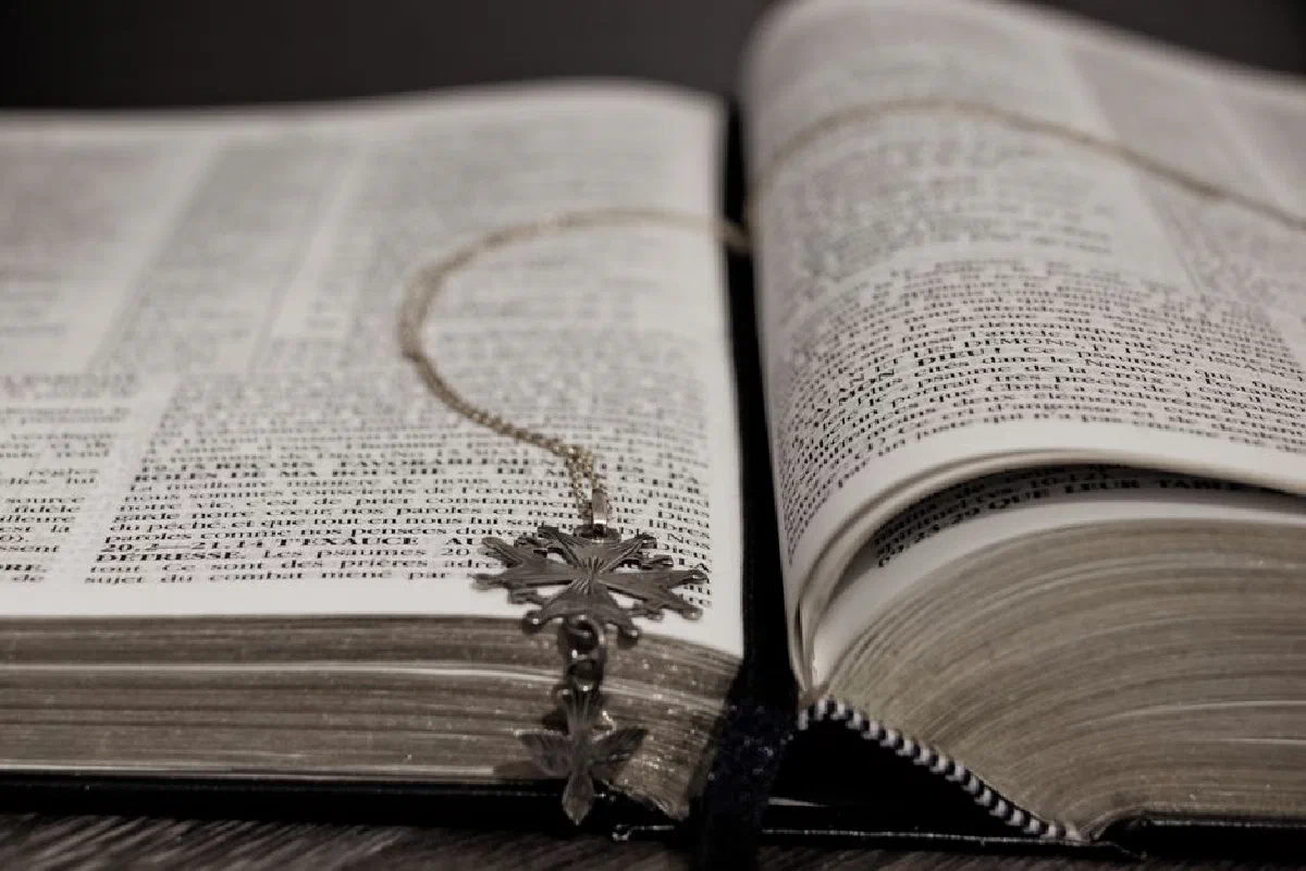 An open Bible with a cross necklace resting on its pages, symbolizing faith and spirituality.