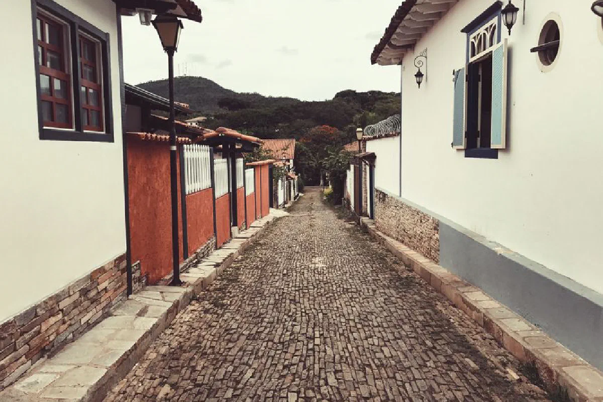 Rough narrow walkway between aged buildings near mountain under cloudy sky in city