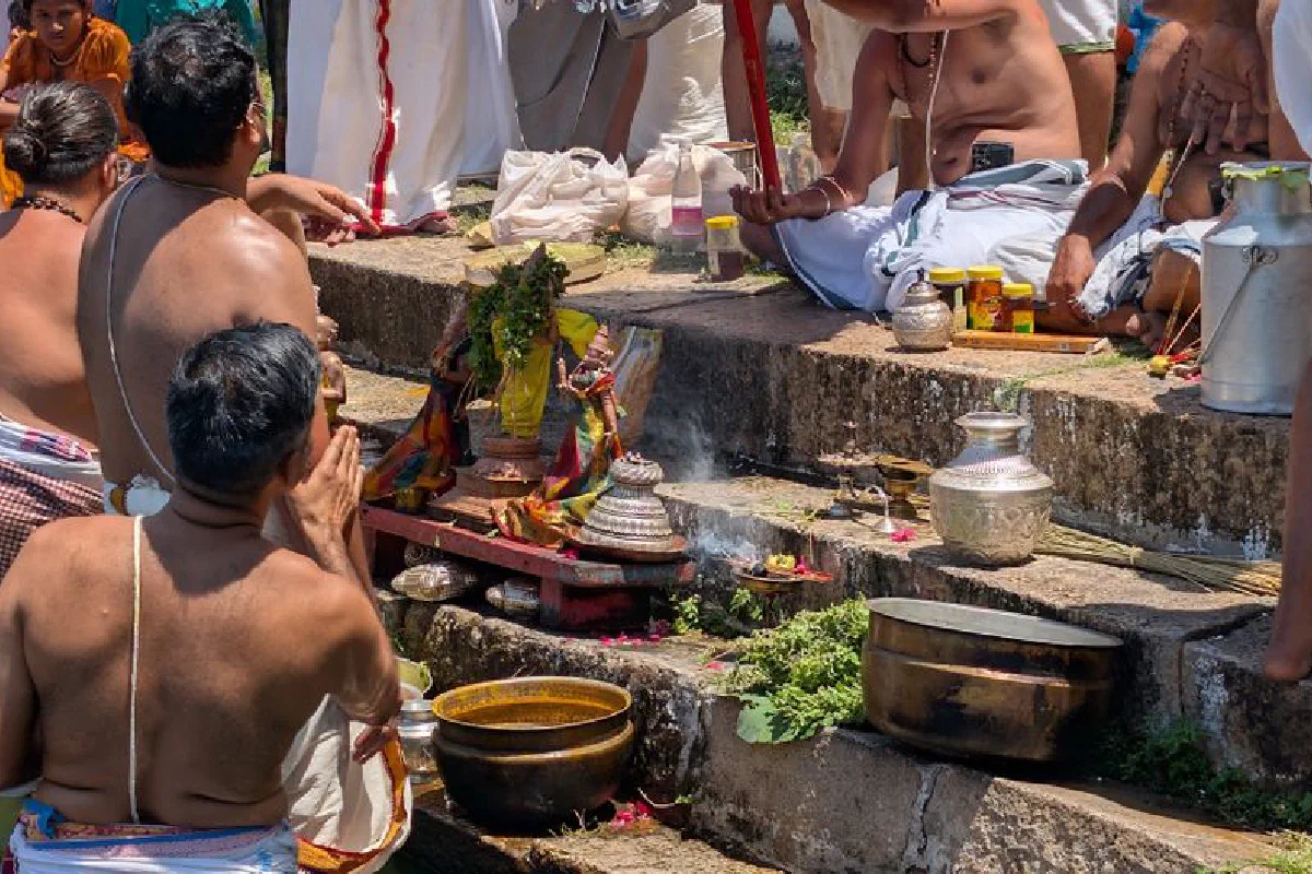 A vibrant Hindu ceremony taking place at a riverbank, featuring traditional attire and offerings.