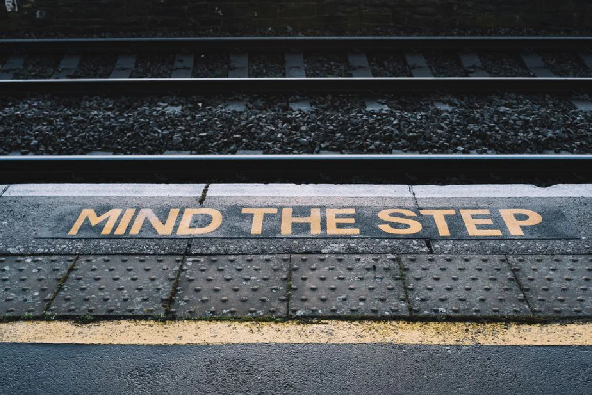 Metal platform with yellow inscription marking near railroad on city street in daytime