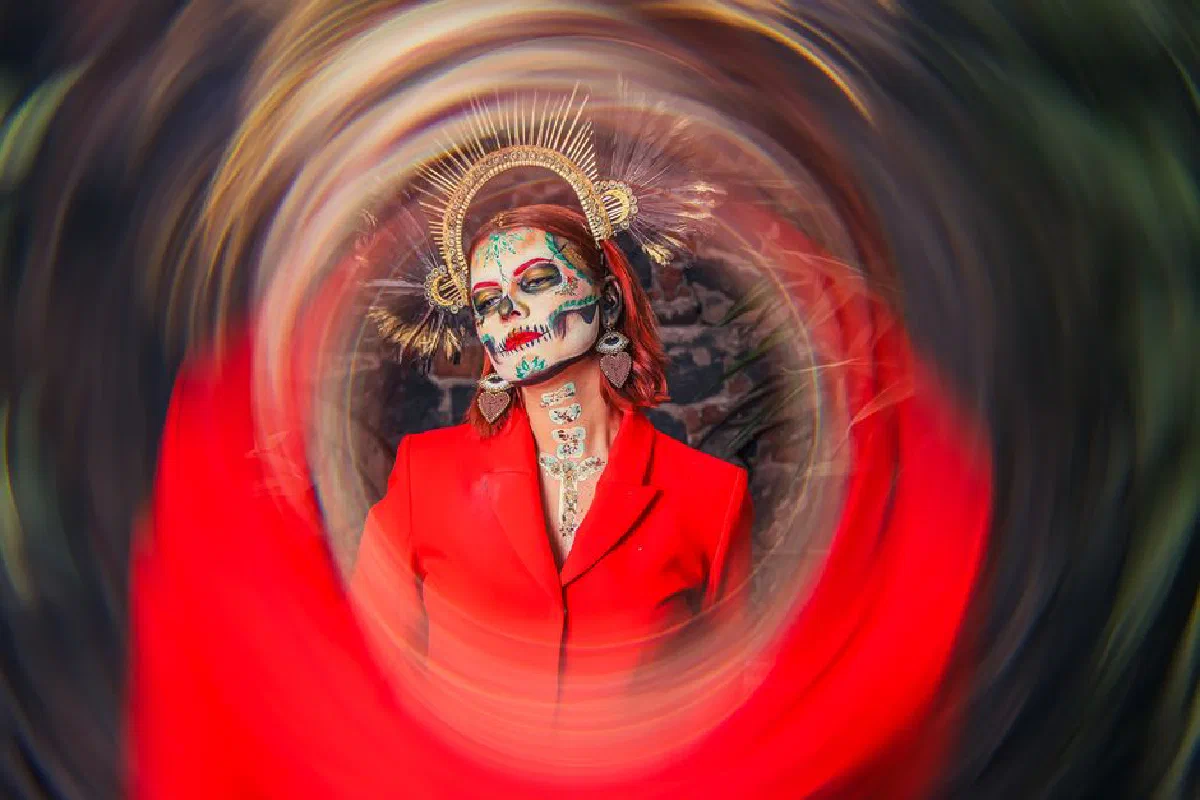 Colorful Day of the Dead makeup portrait with artistic swirl effect.