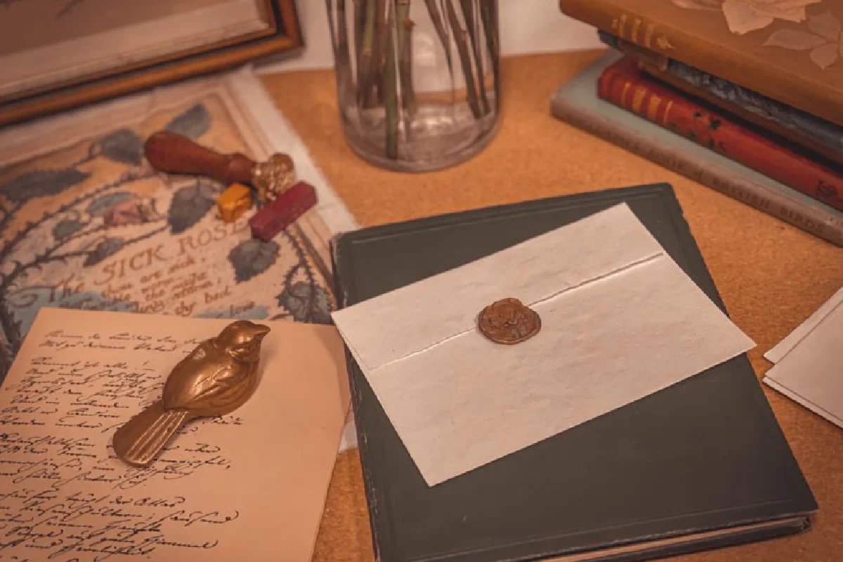 A vintage desk setup featuring a wax-sealed letter, books, and a figurine, evoking a nostalgic and retro atmosphere.