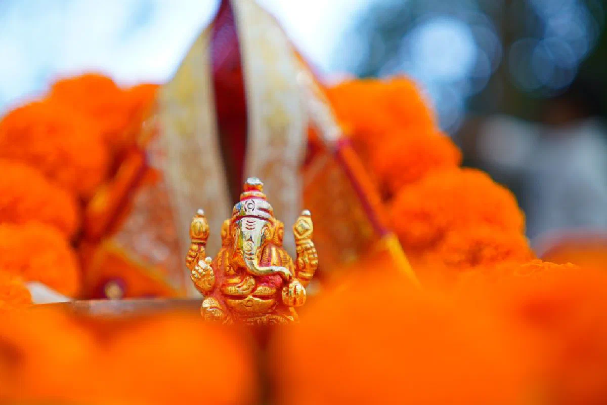 A detailed photo of a Lord Ganesha idol amidst vivid orange marigolds, capturing vibrant Hindu culture.