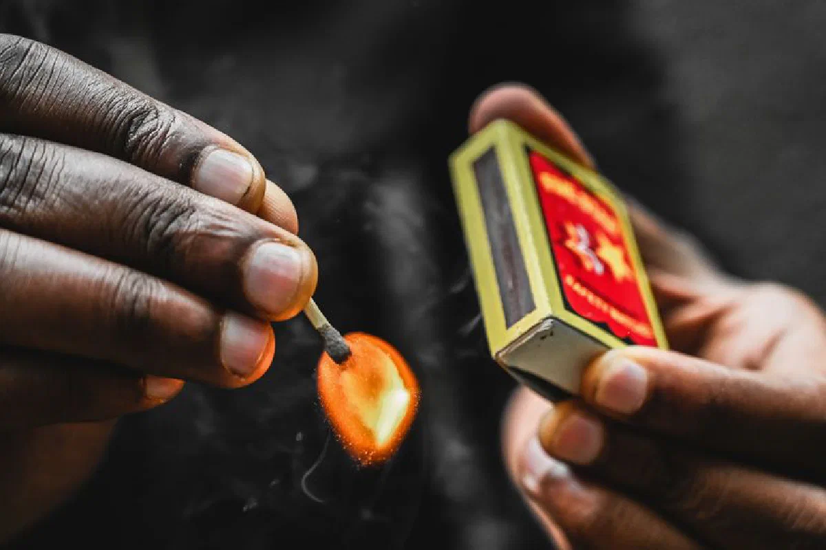 A detailed close-up of hands igniting a matchstick, showcasing the flame and action.