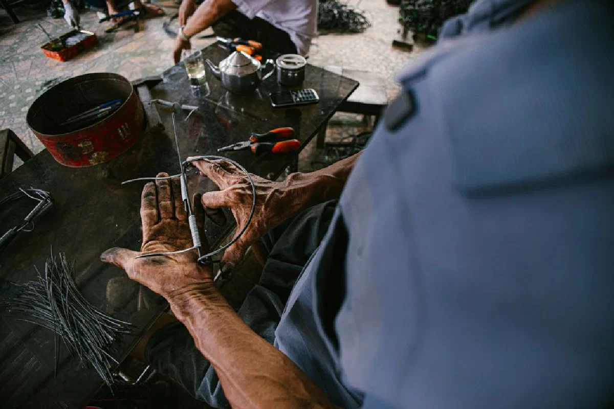 A skilled artisan shaping metal by hand in an industrial workshop setting.