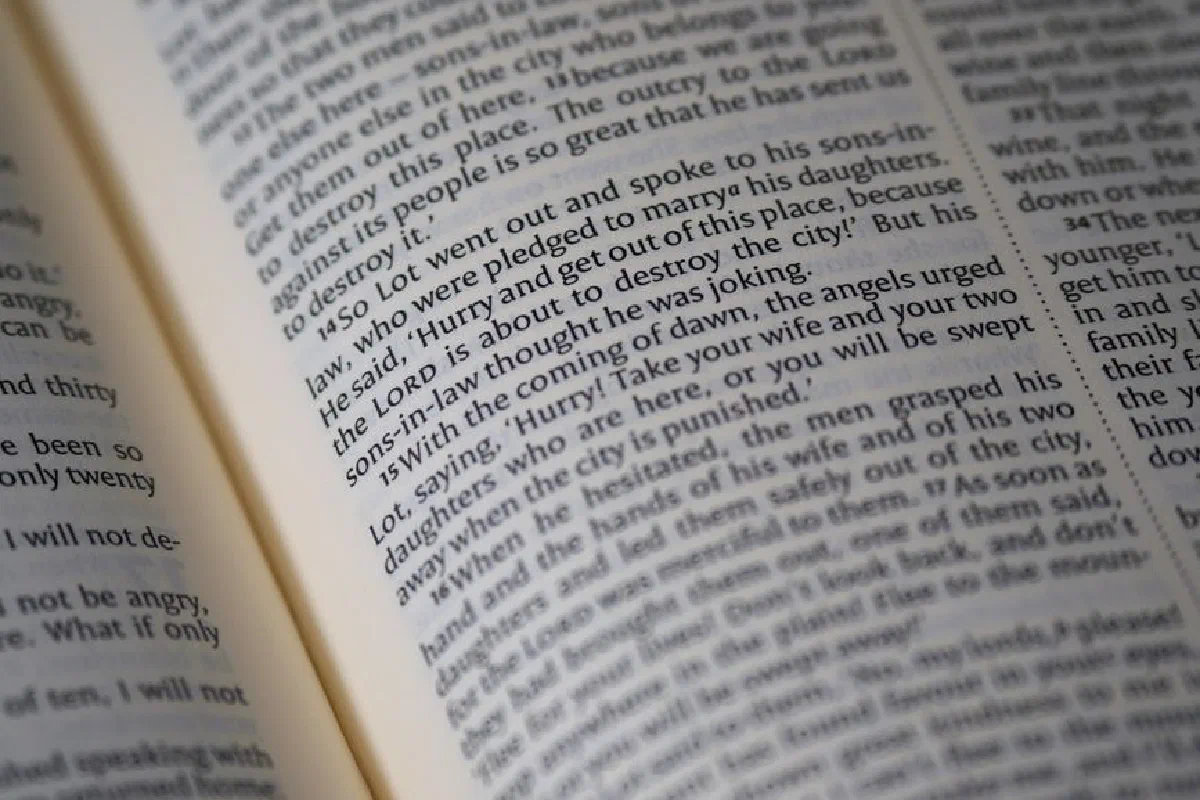 A detailed close-up of a Bible page showing scripture text and verses.
