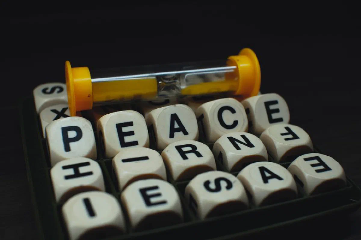 A creative arrangement of dice spelling 'PEACE' with an hourglass, symbolizing time and tranquility.