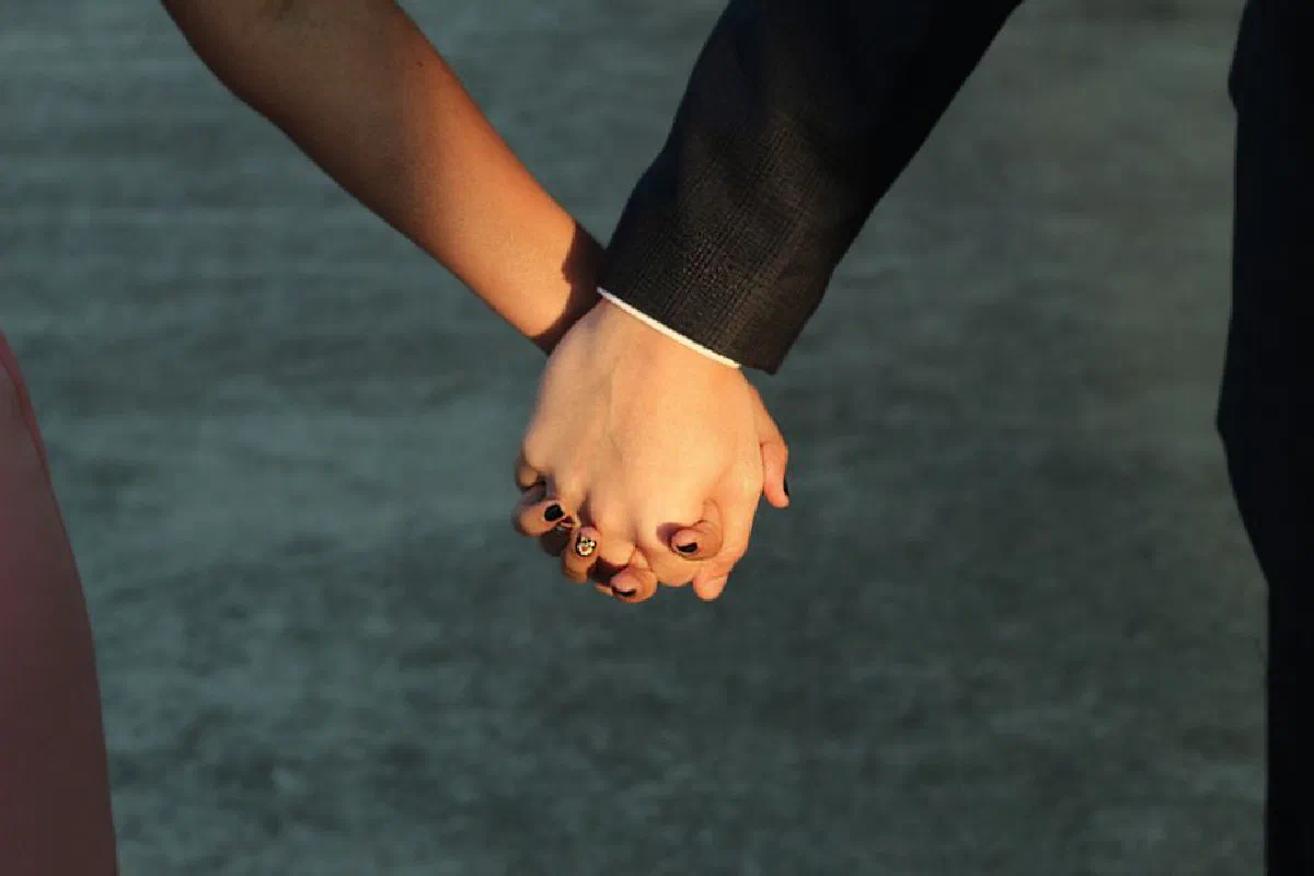 A couple holding hands outdoors, symbolizing love and connection.