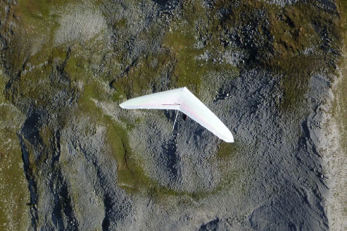 Aerial shot of a hang glider soaring over the rocky terrain of Provence-Alpes-Côte d'Azur, France.