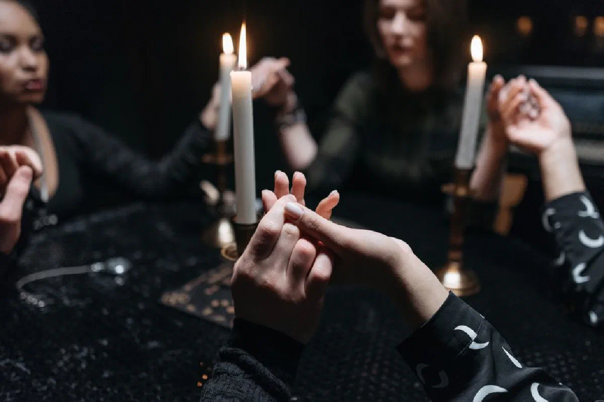 A mystical seance with women holding hands around candles, creating a spiritual ambiance.