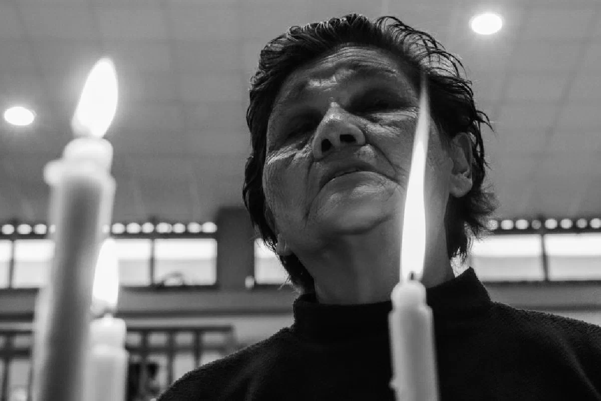 A senior woman reflects near candles in a peaceful indoor setting, capturing solitude and contemplation.