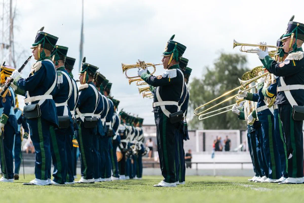 Military band performing outdoors on a sunny day in uniform.