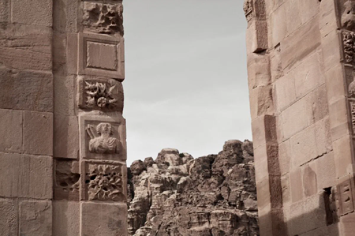 Detailed view of Petra's ancient ruins with intricate stone carvings against rocky backdrop in Wadi Musa, Jordan.