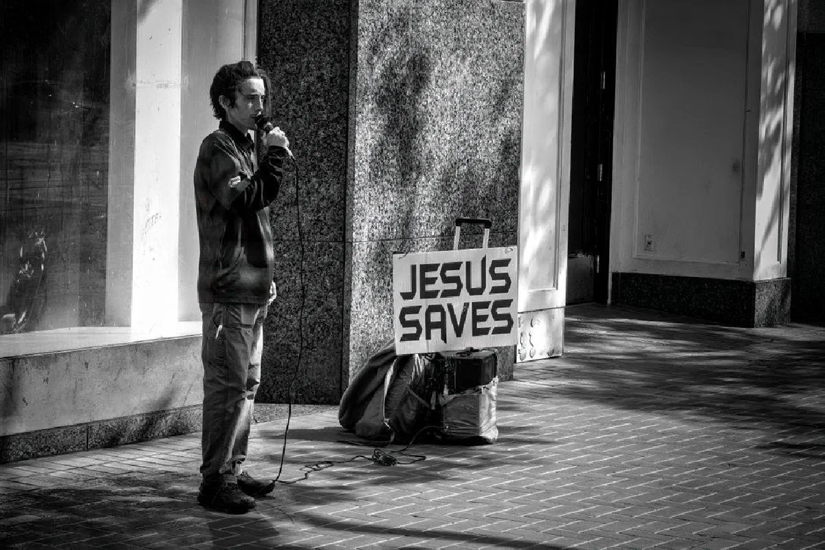 Man preaching with 'Jesus Saves' sign on San Francisco street corner.