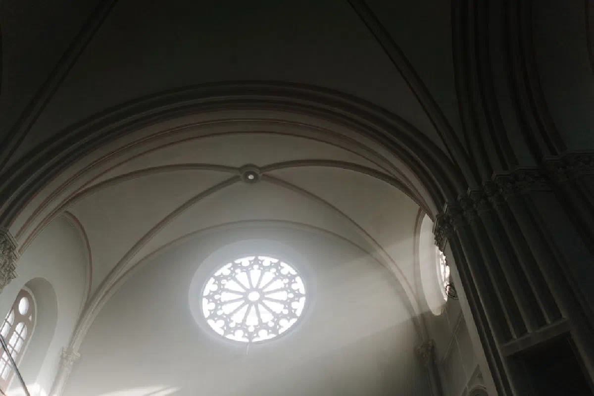 Architectural detail of a Gothic cathedral interior with light streaming through stained glass.