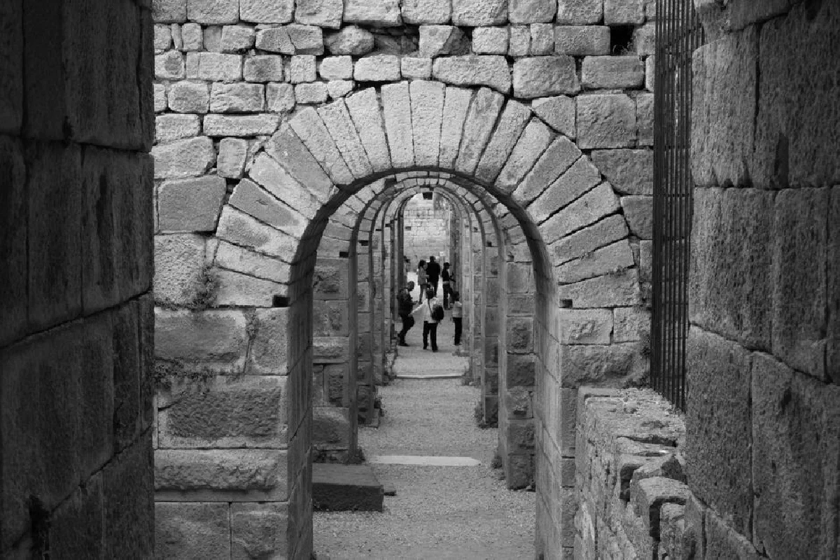 Black and white view of historical stone arches with people in the distance.