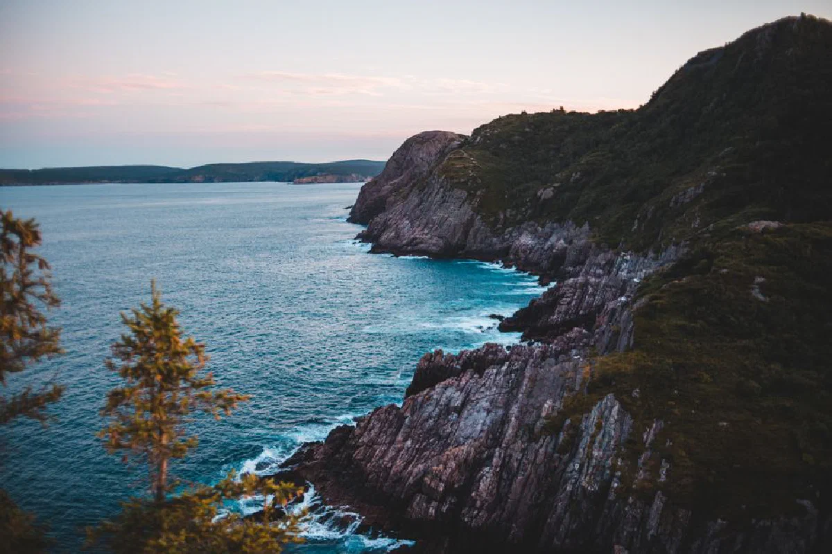 Blue sea water rolling and splashing near rough rocky shore during sunset in nature