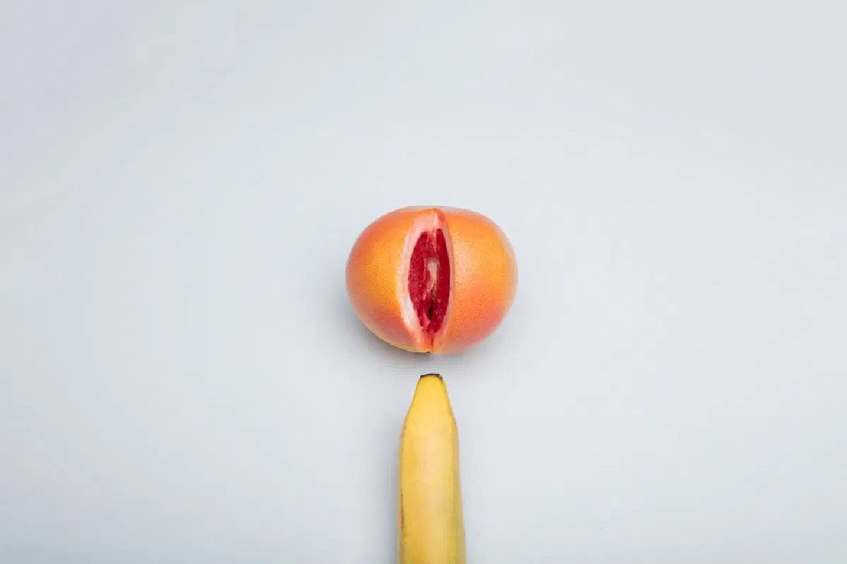 Conceptual fruit arrangement featuring a banana and grapefruit on a white background.