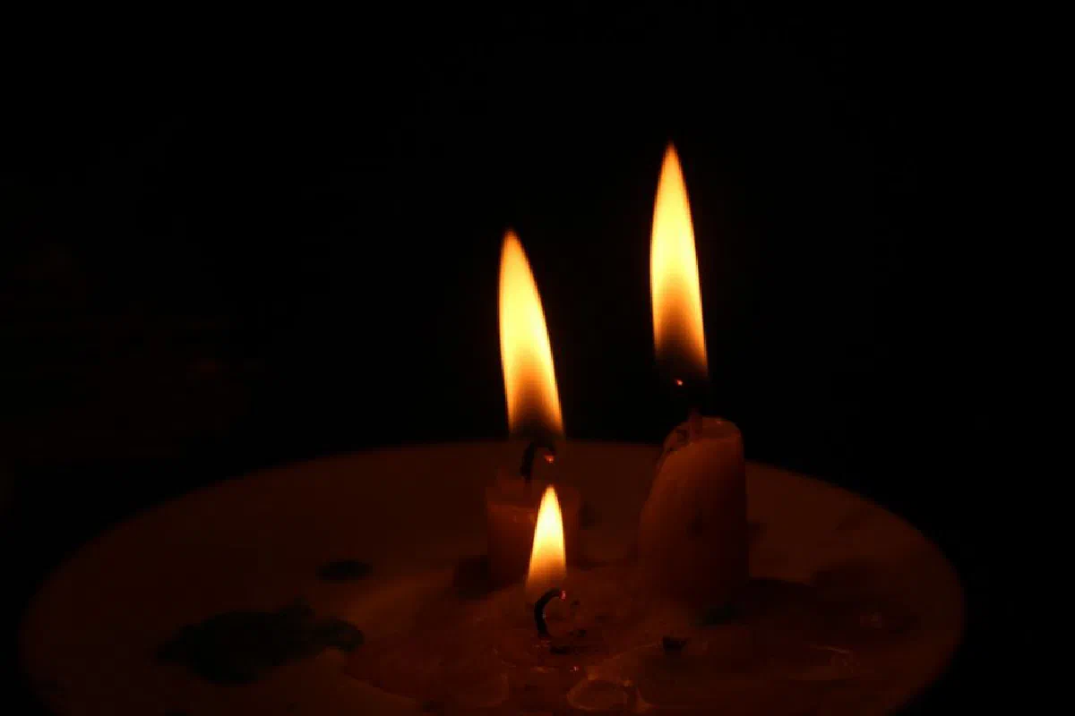 Three lit candles casting a warm glow in the dark, creating a serene and calming atmosphere.