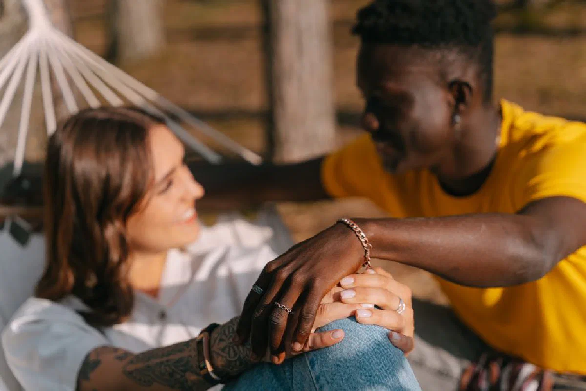 A joyful couple enjoying a sunny day together in a hammock, sharing a delightful moment outdoors.