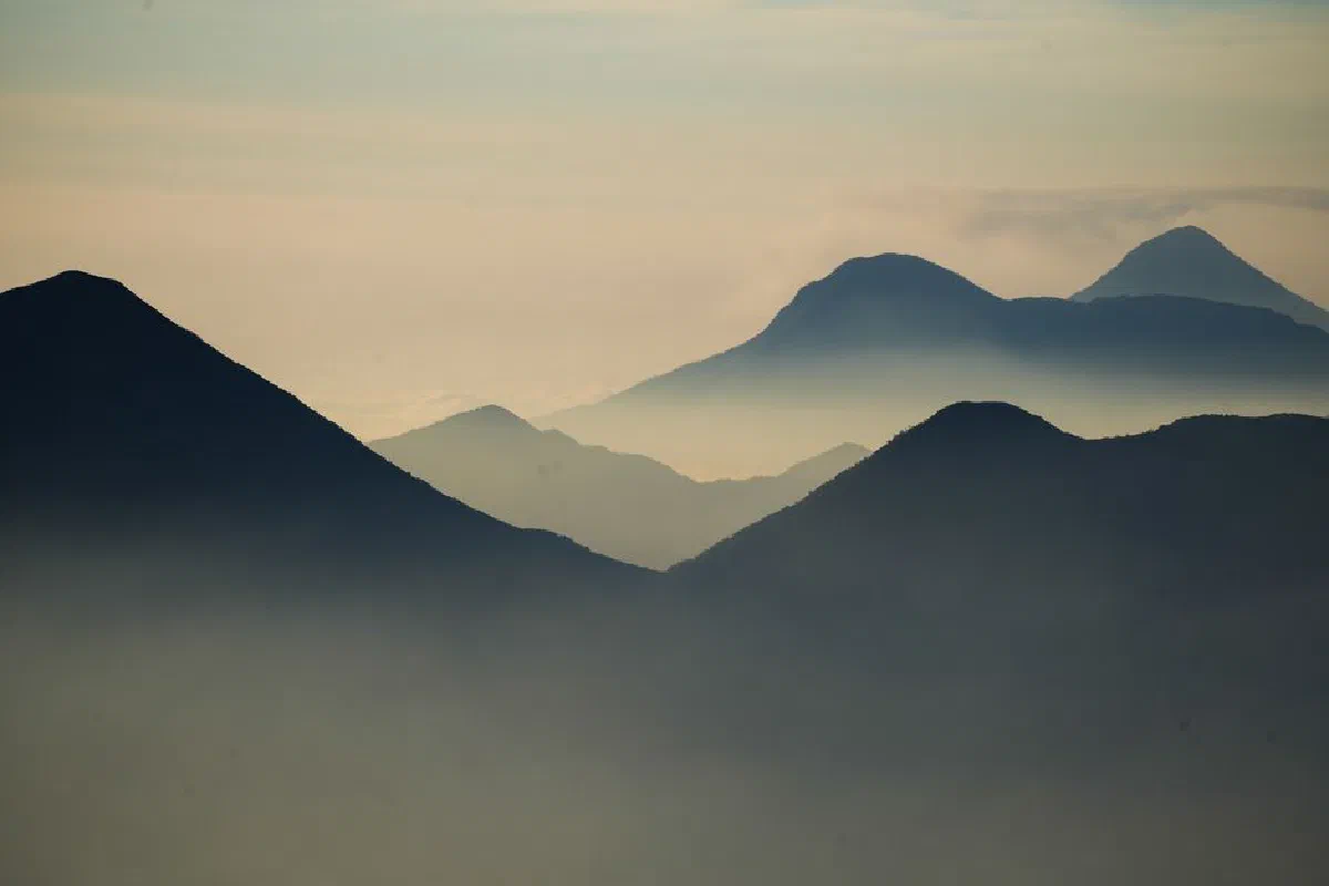 Peaceful misty mountain silhouettes at dawn, creating a tranquil and ethereal atmosphere.