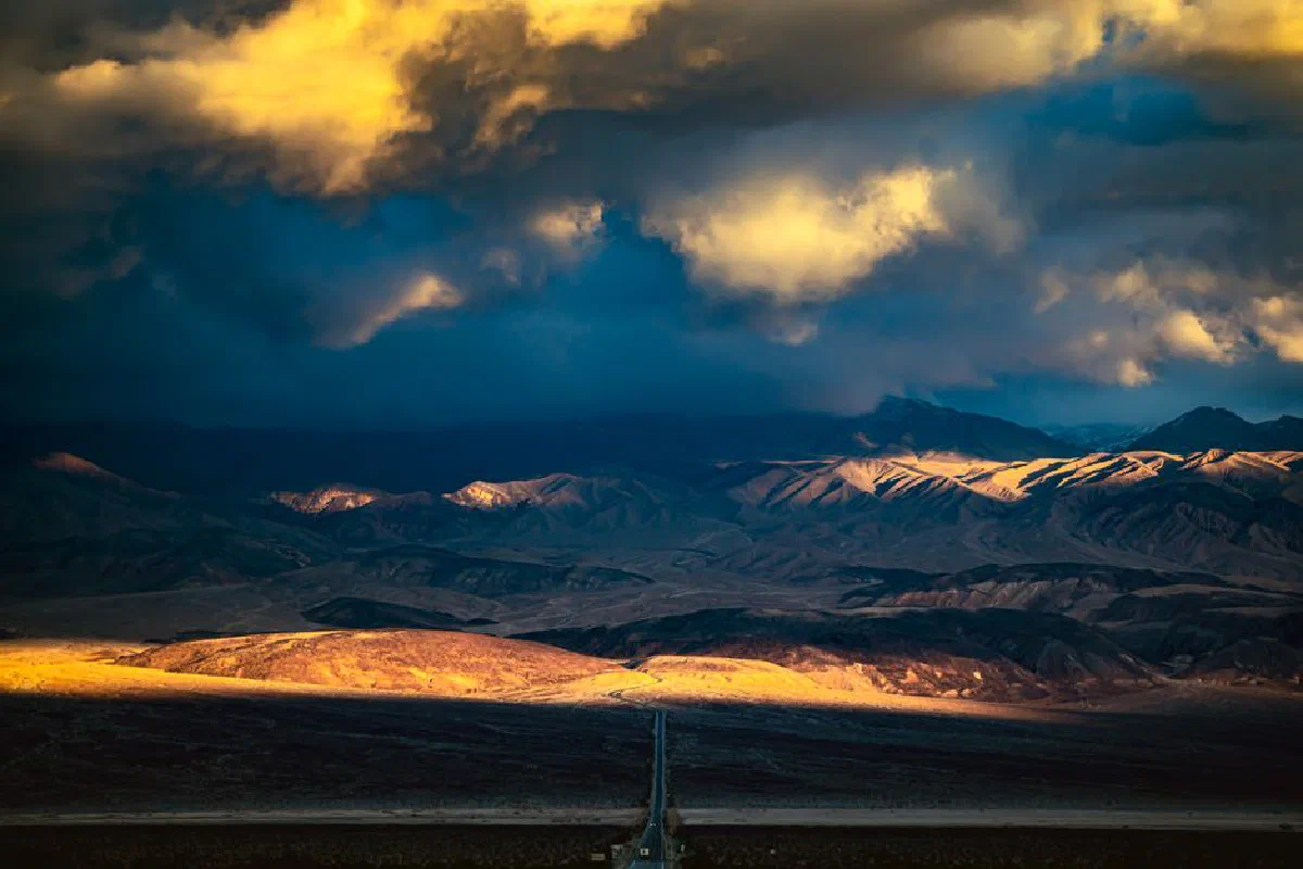 Stunning desert landscape with dramatic skies and majestic mountains illuminated by sunset light.