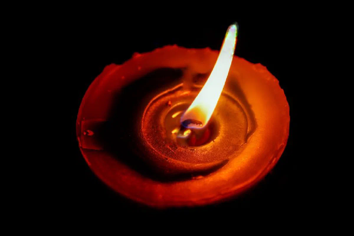 Close-up of a red candle's flickering flame, creating a warm glow against a black background.