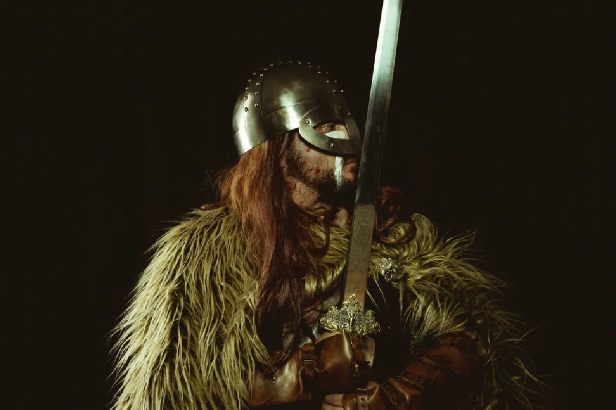 A Viking warrior in armor holding a sword, showcasing historical attire.