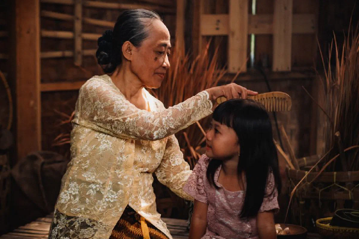 Heartwarming scene of a grandmother and granddaughter sharing a tender moment in a traditional Indonesian home.