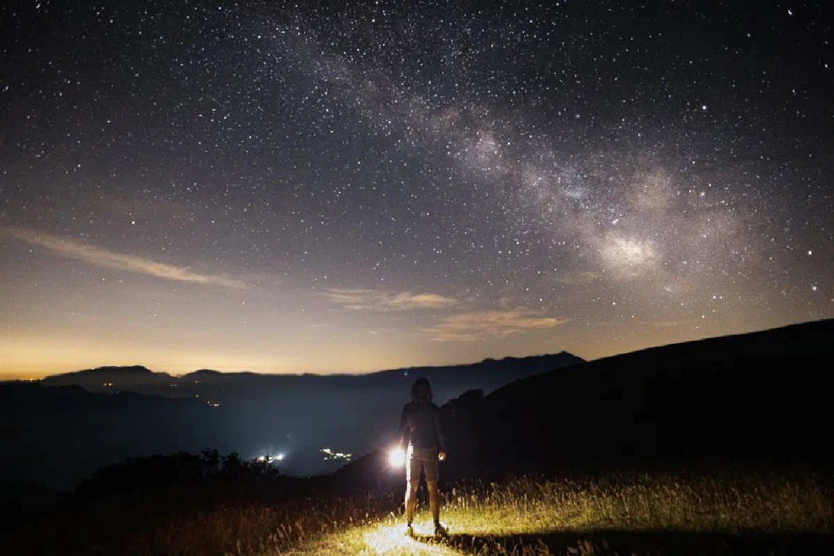 Person stargazing under the Milky Way on a clear night, capturing the celestial beauty.