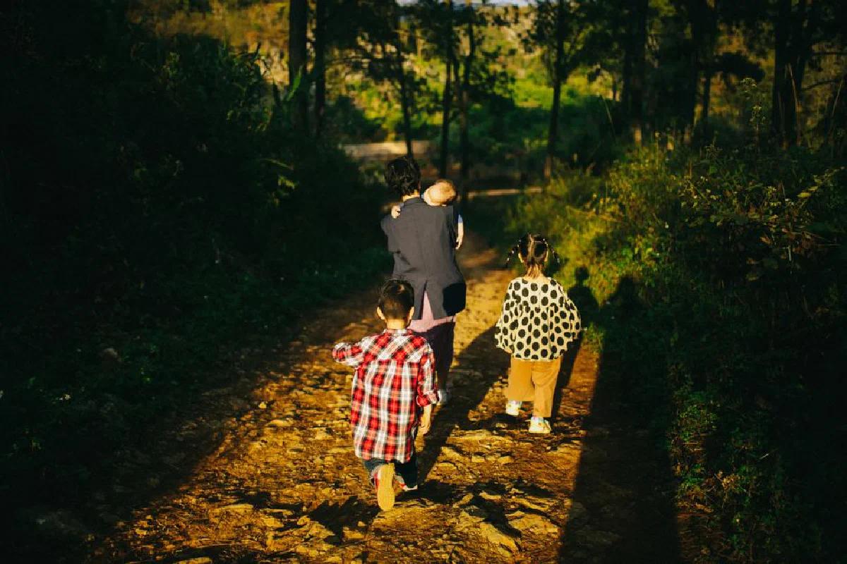 A family of four walking down a sun-drenched forest path, enjoying a peaceful day outdoors.