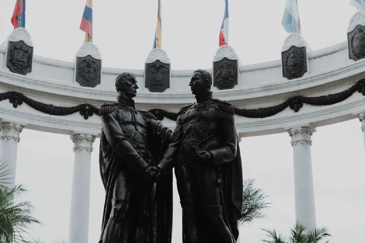 Statues at Hemicycle de la Rotonda in Guayaquil, Ecuador with flags above, highlighting cultural heritage.