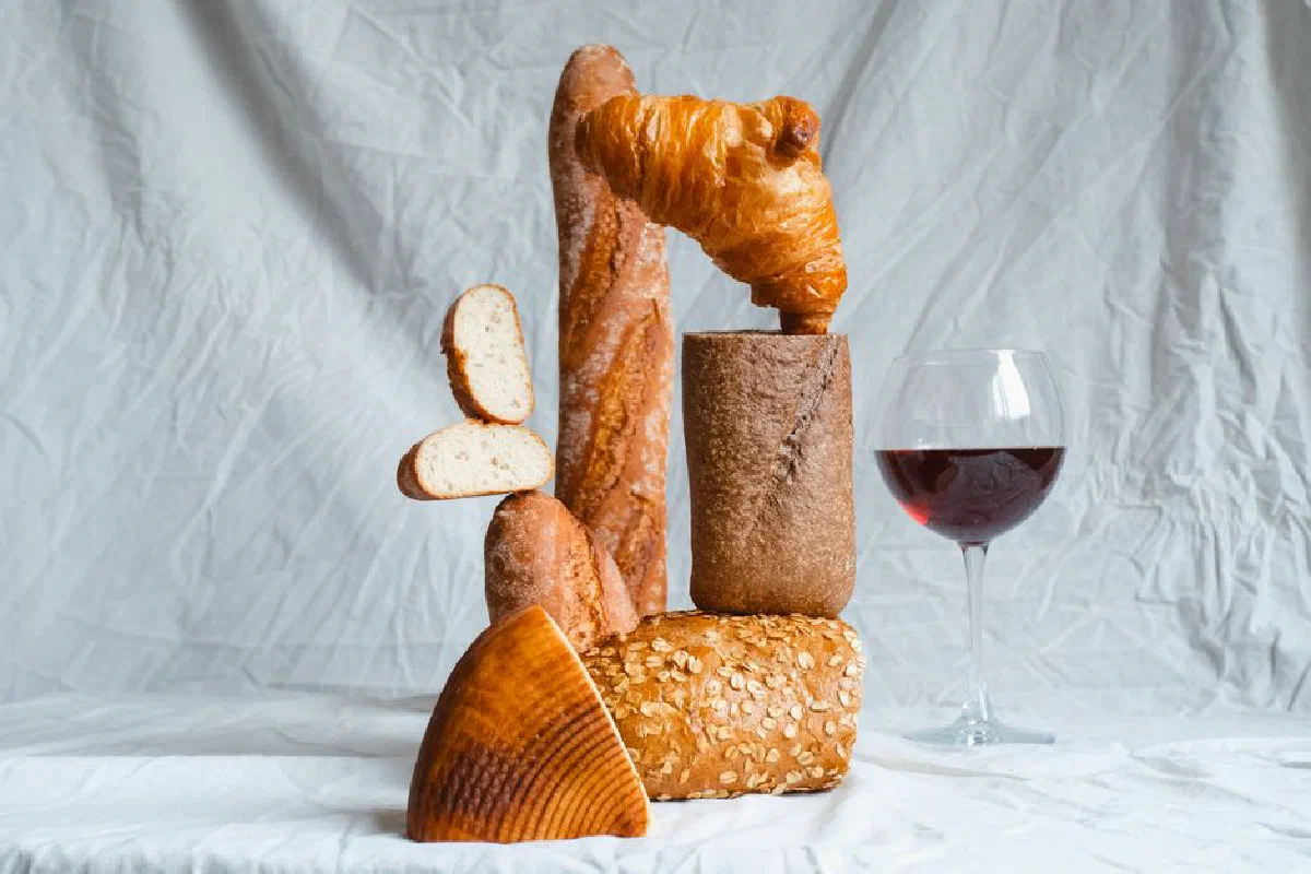 Creative still life of assorted breads with a glass of red wine.