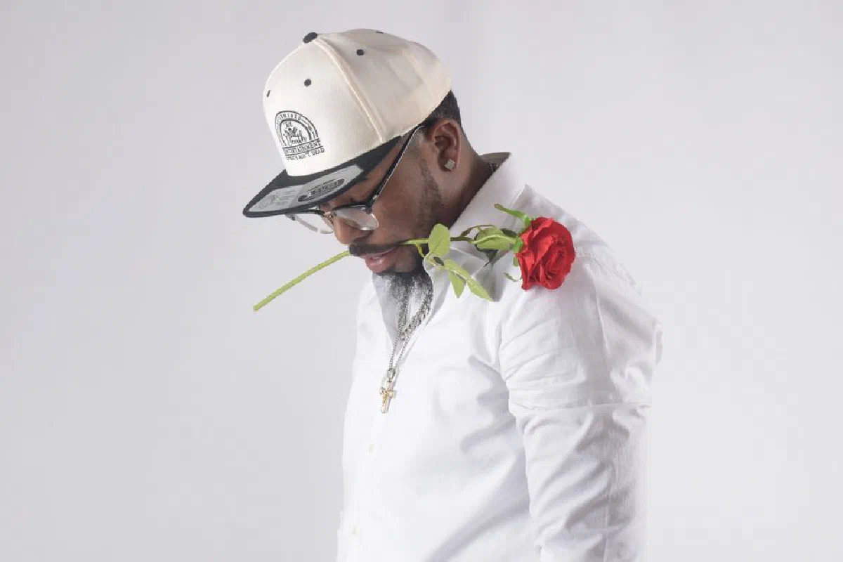 Fashionable man wearing sunglasses with red rose, exuding stylish romantic vibe.
