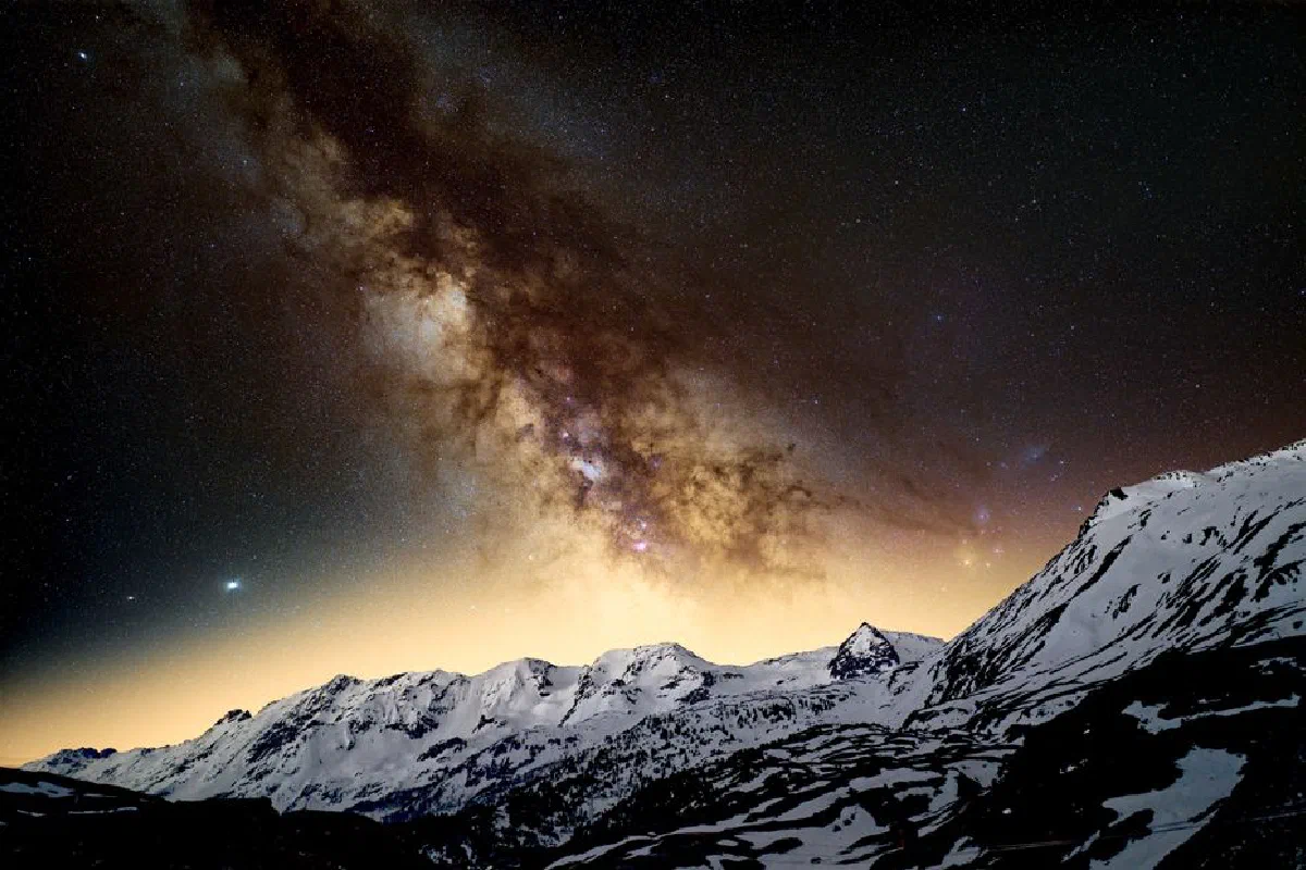 Stunning view of the Milky Way illuminating snow-capped mountains at night.